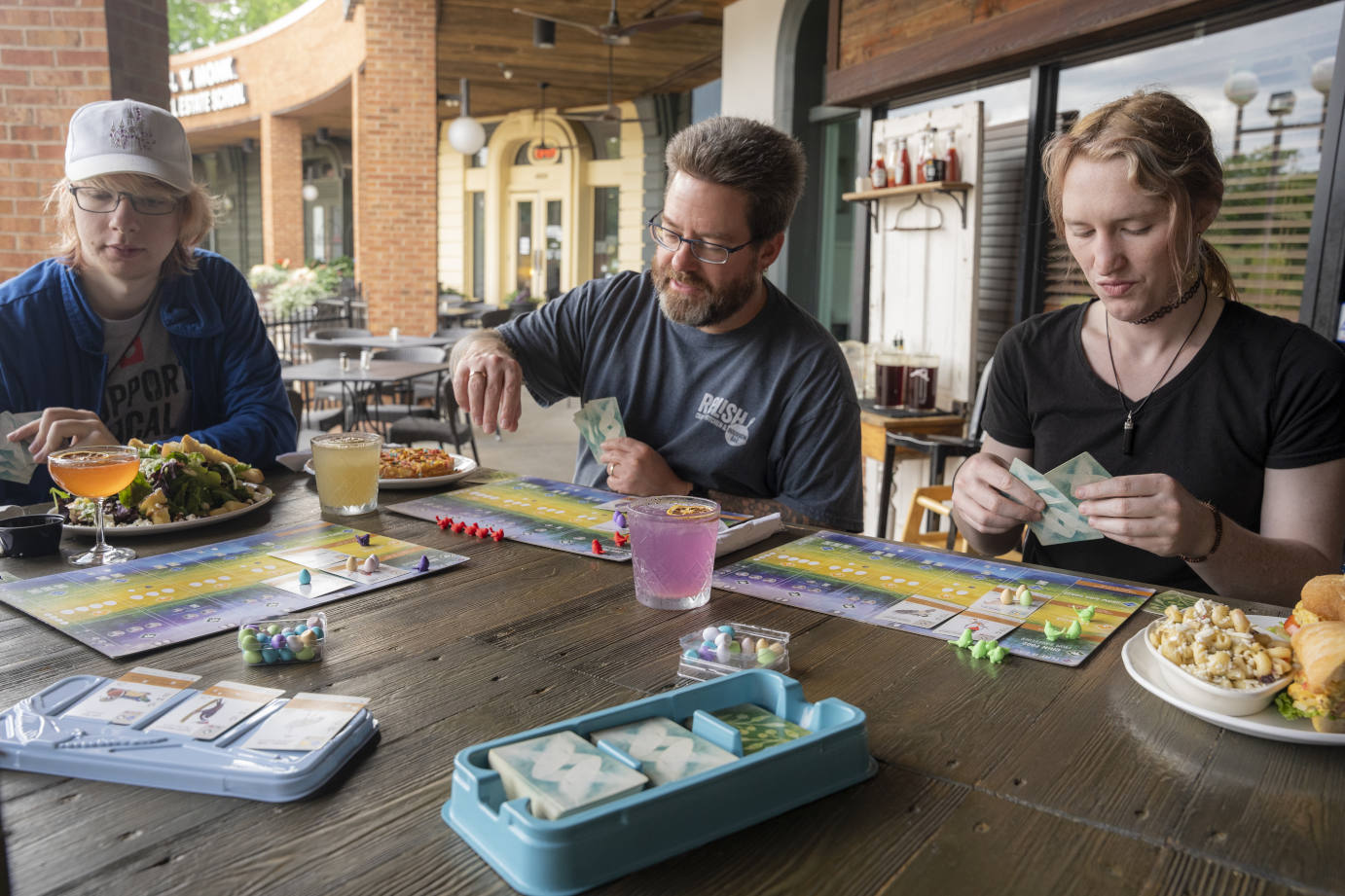 Exterior, guests playing a board game at a table with served dishes and drinks